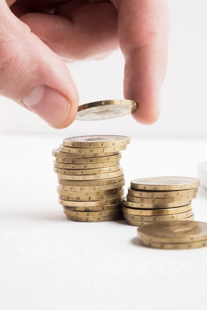 Mano apilando monedas de oro sobre un fondo blanco, simbolizando el ahorro económico y la rentabilidad de las ayudas para rehabilitar viviendas en Galicia.